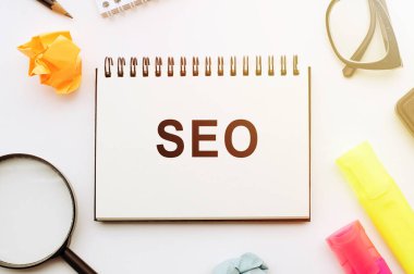 SEO 'nun içinde gözlüklü, büyüteçli, kalemli ve kırışık çarşaflı bir masanın üzerinde metin olan not defteri