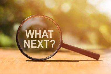 Ahşap masada güneş ışığında sırada ne olduğunu yazılı büyüteç. İş konsepti