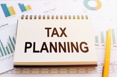 Vergi planlama sözcüğü not defteri tarafından sarı kalemli finansal grafikler üzerine yazıldı