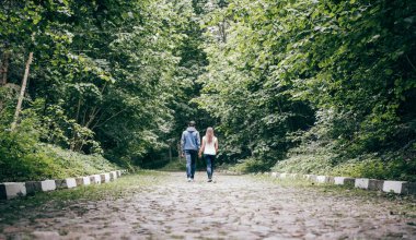 Aşıklar sonbahar parkında el ele yürür