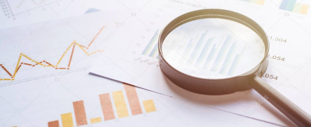 Business concept with magnifying glass on documents. Business grafs and charts