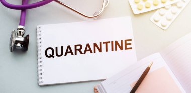 Masanın üzerine tıbbi not defteriyle yazılmış karantina metni