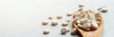 Beyaz haplar, mavi masadaki tahta kaşıkta tabletler. Tıp ve sağlık konsepti. Eczacılık. Üst Manzara. Haplar ve vitaminler.