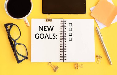 Yeni hedefler, plan, ofis aksesuarlarıyla birlikte not defterindeki aksiyon metni. İş motivasyonu, ilham kavramları