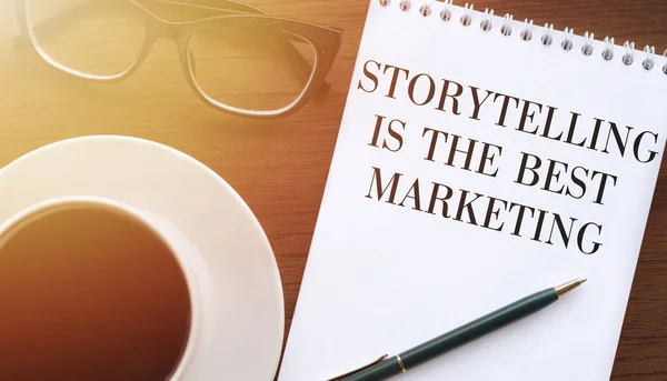 Storytelling is the best Marketing - written on a notebook with a pen and coffee