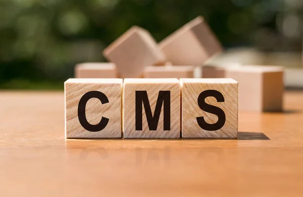 Acronym CMS - content management system. Wooden small cubes with letters on table. Business Concept image.