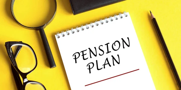 Pension Plan concept with notebook,magnifier, glasses and pencil on yellow table
