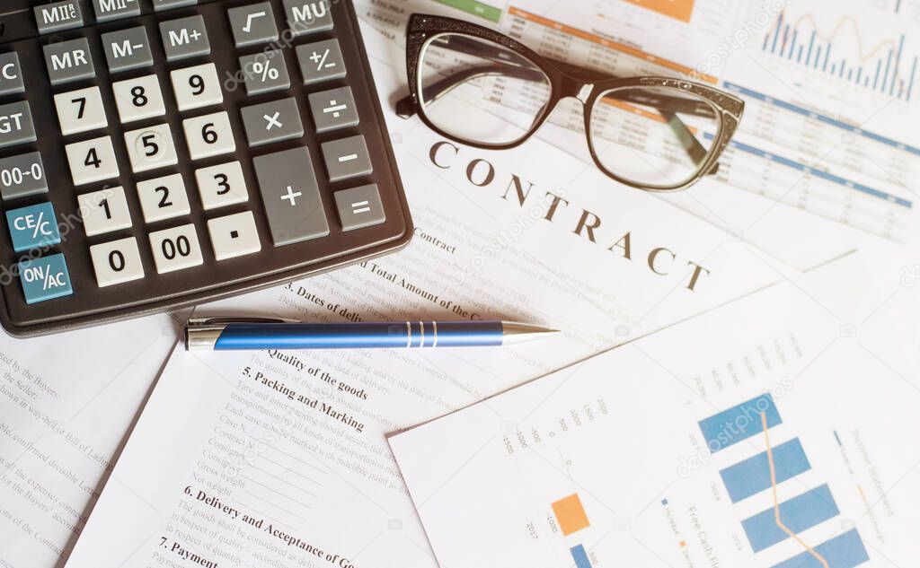 Business concept with calculator glasses and pencil on documents. Business grafs and charts. Contract