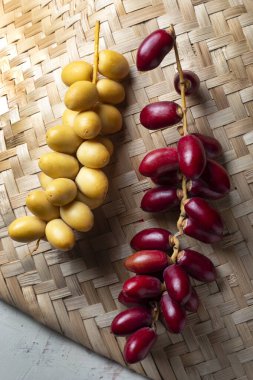 Taze sarı ve kırmızı hurma, bambu hasırı üzerinde.
