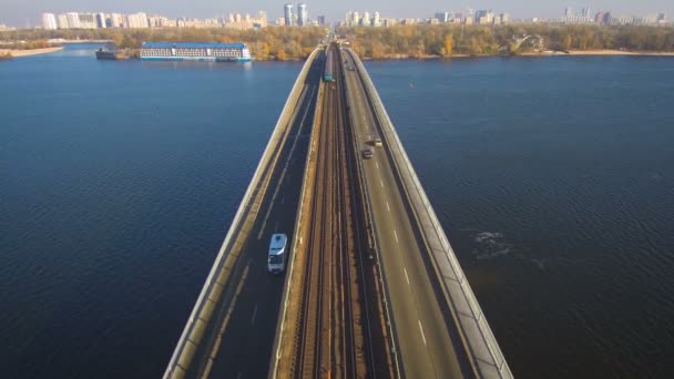 Aerial, top view from Drone: Metro train travels over a bridge with cars and trucks. — Stock Video