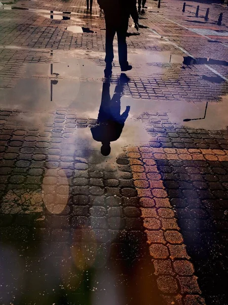 Su birikintisinde yürüyen bir adamın yansıması..