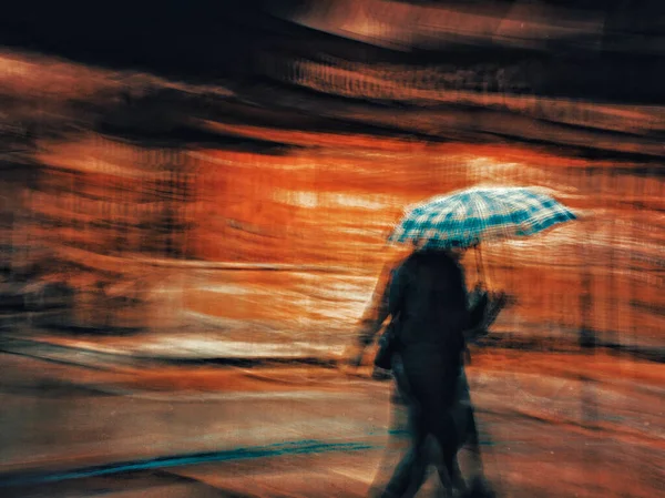 Long exposure view of the person walking with umbrella.