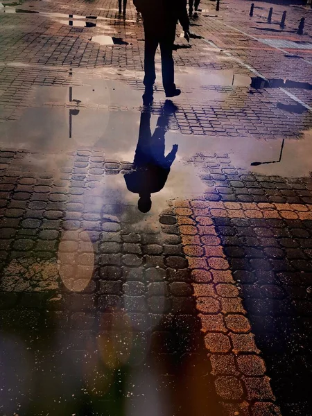 水の水たまりの上を歩く男のシルエットの反射 ストック写真