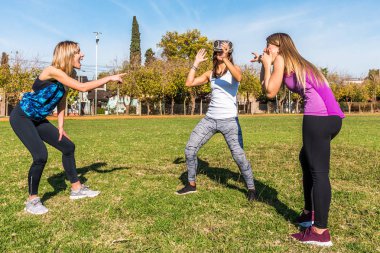 Parkta üç Beyaz kadın iki sarışın ve sanal gerçeklik maskesi ile bir esmer