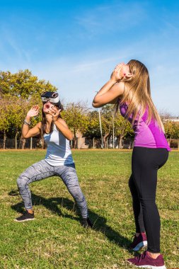 Parkta iki Beyaz kadın, bir sarışın ve sanal gerçeklik maskesi ile başka bir esmer