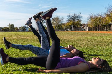 Parkta üç beyaz kadın, iki sarışın ve bir esmer parkta çalışıyor. Spor, sağlık ve yaşam tarzı kavramı