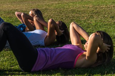 Parkta üç beyaz kadın, iki sarışın ve bir esmer parkta çalışıyor. Spor, sağlık ve yaşam tarzı kavramı