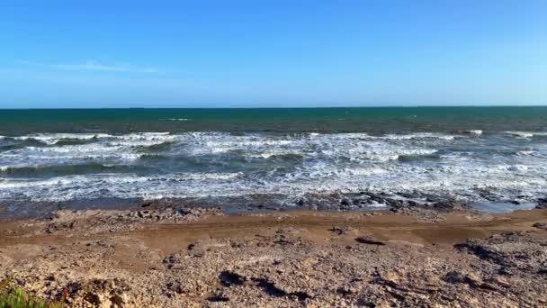 青い空と岩の多い海岸に到着する多くの波で地平線までの海の景色 — ストック動画