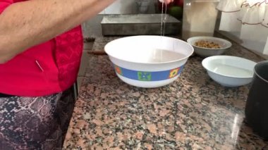 Yetişkin bir kadın iki yumurta kırıyor ve bir kaseye koyuyor. Coronavirus karantinasından sonra konsept evde kalmak için kapalı aktivite.