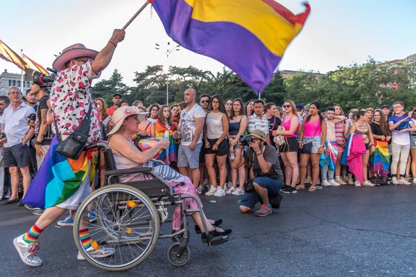 Madri, Espanha - 06 de julho de 2019: em Madri, celebrações do dia do orgulho gay. Uma mulher em uma cadeira de rodas carregada por um homem . — Fotografia de Stock