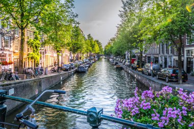 Amsterdam, Hollanda - 19 Temmuz 2018: Amsterdam 'daki kanallardan birine çiçekli bir köprüden bakmak.