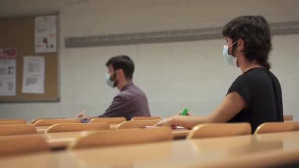 University students wearing face masks sitting in empty classroom due to Coronavirus Pandemic — Stock Video