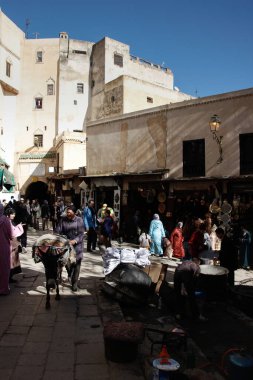 Fas 'taki Old Fez Medina' da Seffarine Meydanı 'nda eşeğin üzerinde mal taşıyan tüccarlar var..
