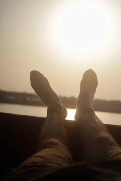Legs of a Man who is resting at sunset. Feet wearing socks in summer holiday time