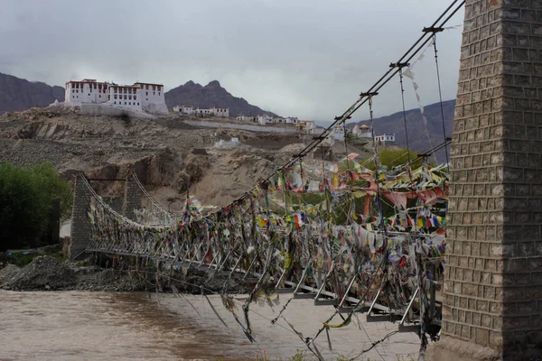 金属製の橋は インド北部のチベット州ラダックの仏教寺院につながる仏教の旗を祈ることで覆われています — ストック写真