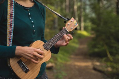 The Nature 'da Ukelele çalan bir kadının elleri. Ormanda müzik çalan kız.