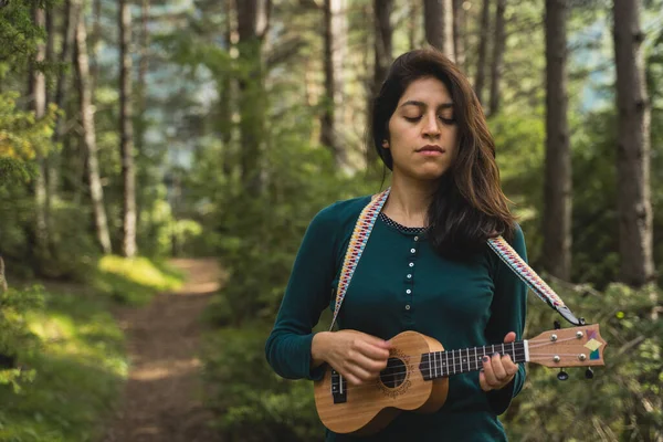 The Nature 'da Ukelele' yi oynayan genç çekici kadın. Ormanda müzik çalan güzel kız.