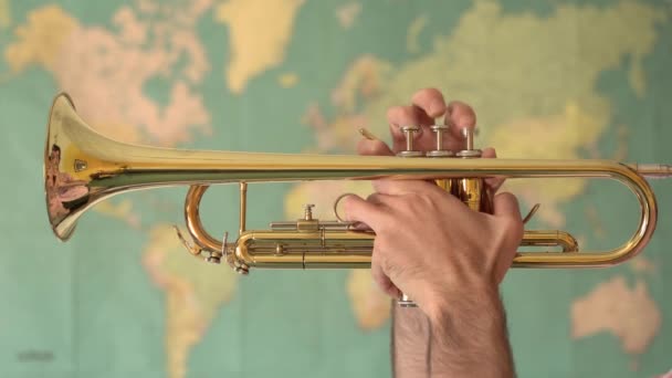 World Music. Mãos de homem tocando trompete na frente de um Mapa Mundial — Vídeo de Stock