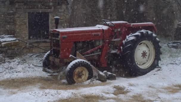 Verlassener roter Traktor unter dem an einem verschneiten Wintertag — Stockvideo