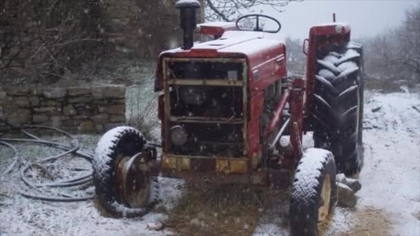 Verlassene Landmaschinen an einem verschneiten Wintertag. Roter Traktor unter dem Schnee — Stockvideo