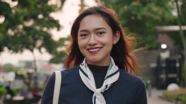 Şehirdeki kameraya gülümseyen güzel bir Asyalı kadın.