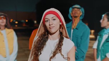 Geceleri dans ekibiyle şehirde poz veren trend bir kadının portresi. Kentsel yaratıcılık, ifade ve özgürlük