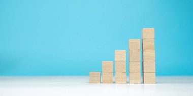 Ahşap bloklar mavi arka planda piramit merdiven olarak kullanılıyor. Başarı, büyüme, kazanç, zafer, kalkınma veya en üst düzey konsept