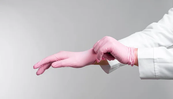 Mãos Médico Feminino Colocando Luvas Estéreis Rosa Isoladas Fundo Cinza — Fotografia de Stock