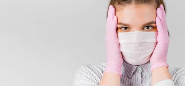 Beyaz gömlekli, tıbbi maskeli ve pembe steril eldivenli güzel bir kadın el ele tutuşuyor. Şok oldu. Kendini izole etme, koruma, karantina ve salgın konsepti