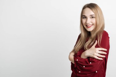 Aşk, şefkat konsepti. Çekici Avrupalı genç bir kadın, uzun sarı saçları ayakta, kollarını göğsünde birleştirmiş, gri arka planda. Metnin için boşluk kopyala