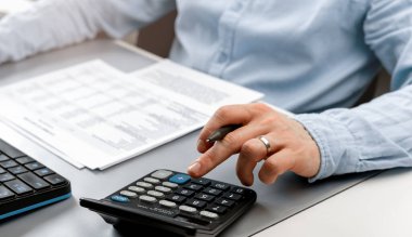 Yakın plan işadamı kağıt döküman finansal verileri hesaplıyor. Finans kavramı