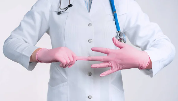 Widok Kobiety Lekarza Mundurze Zakładanie Różowych Jałowych Rękawiczek Izolowanych Białym — Zdjęcie stockowe