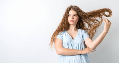 Çekici Avrupalı bir kızın portresi, hoşnutsuzca başını eğmiş ve kıvırcık saçlarını sallıyor. Beyaz arka planda izole edilmiş. Metnin için boşluk kopyala