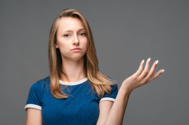 What the hell are you talking about, nonsense. Studio shot of frustrated female with blonde straight hair gesturing with raised palm, frowning, being displeased and confused with dumb question