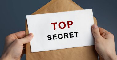 Mavi zemin üzerinde TOP SECRET yazılı el sanatları zarfı taşıyan adamın kırpılmış görünümü, konsept