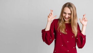 Kazanmak zorundayım! Uzun sarı saçlı neşeli Avrupalı genç kadın parmaklarını çapraz yapıyor, arzulanan dilekler diliyor, gündelik kıyafetler giyiyor, iyi haberleri bekliyor..