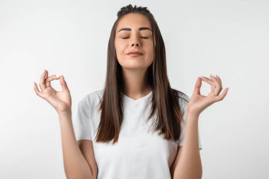 Uzun kestane rengi saçlı çekici sakin Avrupalı kız meditasyon yapan elleri, nirvana nilüfer çiçeği pozu, solunum pratiği yogası, beyaz arka planda izole edilmiş..