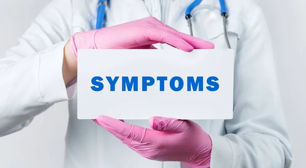 テキストSymptomsでカードを保持白いコートとピンクの滅菌手袋で若い女性医師のクロップビュー 医学的概念 — ストック写真