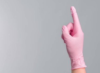 Pembe lastik eldivenli yakın çekim doktoru gri arka planda parmak izi olduğunu gösteriyor. Tıbbi konsept.