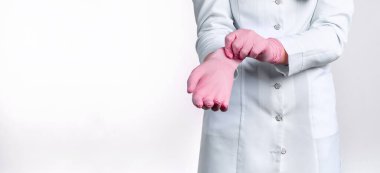 Üniformalı kadın doktorun beyaz arka planda izole edilmiş pembe steril eldivenler giydiği görüntüler. Tıbbi konsept.